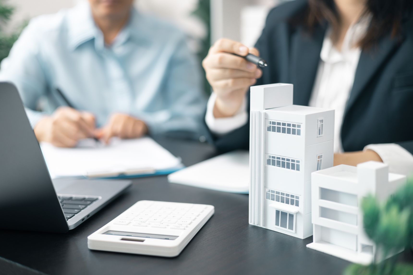 Two colleagues collaborate over a table filled with building figures